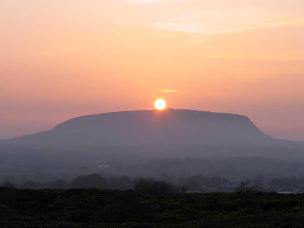 Equinox sunset over Queen Maeve's Cairn viewed from Carns Hill west.