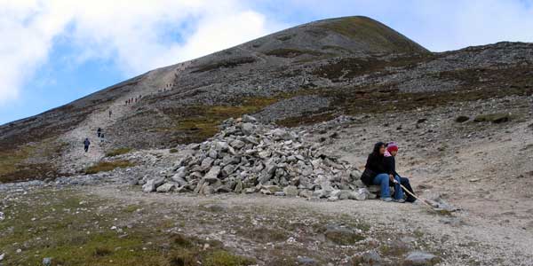 Pilgrims 
        resting on one of the cairns at the base of the summit.