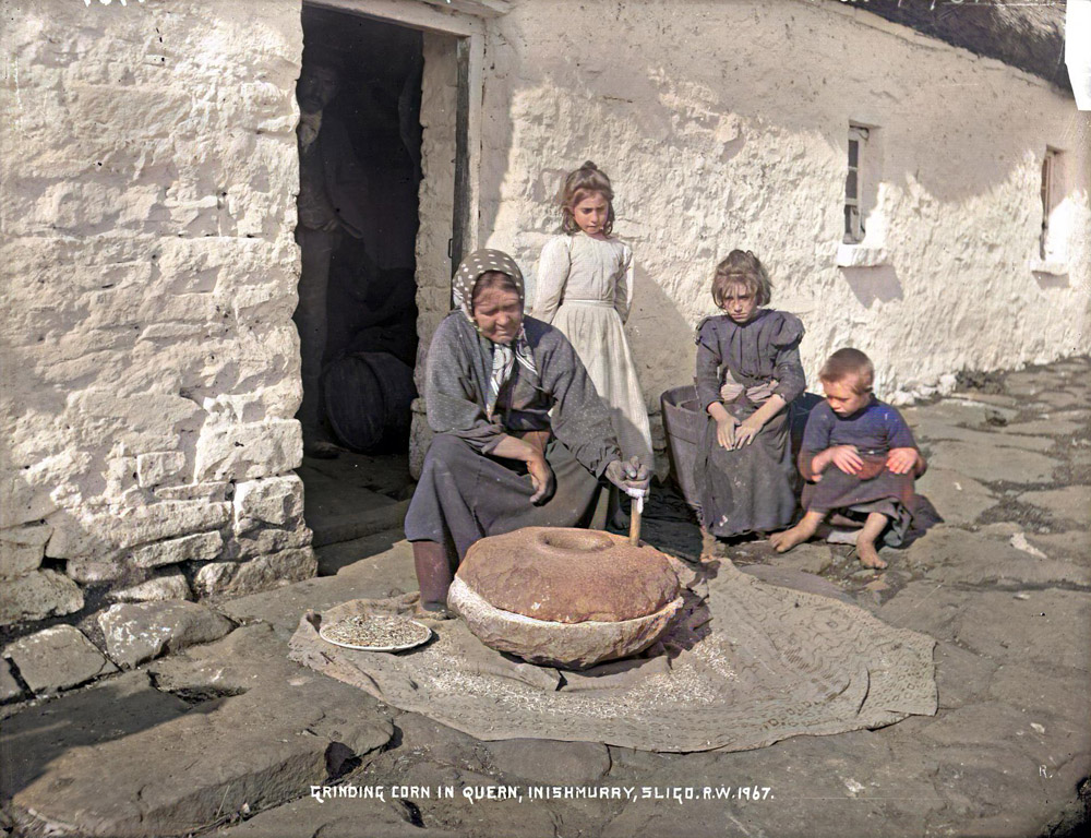 Grinding corn with a hand quern on Inishmurray. Photo by Robert Welch.