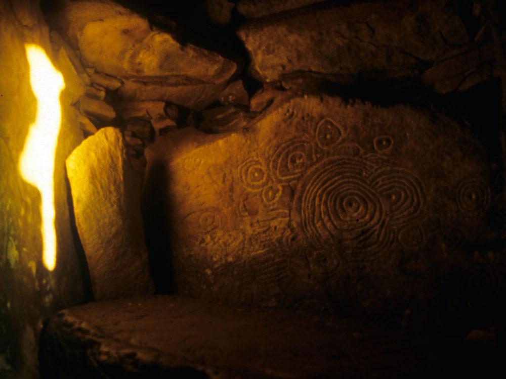 The sunbeam moves towards the small white stone in the corner.